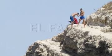 Unos chicos se preparan para saltar desde el borde de un acantilado en la playa de Los Galápagos.