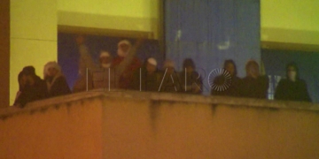 GRA001. MADRID, 19/10/2016.- Fotografía capturada de imágenes de EFE TV. Unos 30 inmigrantes continúan en la azotea del Centro de Internamiento de Extranjeros (CIE) de Aluche más de once horas después de iniciar un motín en el edificio, situado en la madrileña avenida de los Poblados, mientras que la Policía Nacional ha intentado negociar sin éxito con los internos. Los internos permanecen recluidos en la terraza de la parte superior del CIE, aunque solo unos pocos son visibles desde la calle, y algunos portan palos y pancartas hechas en tela en las que se puede leer "libertad". El motín, en el que participaron medio centenar de personas, se inició sobre las 21.15 horas cuando los internos subieron a la parte más alta del centro y comenzaron a arrojar piedras y mobiliario a la vía pública aunque, de momento, se desconoce con exactitud su reivindicación. EFE/EFE-TV