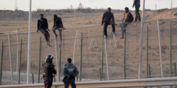 GRA003. MELILLA, 28/05/2014.- Unos 400 inmigrantes de origen subsahariano podrían haber accedido a la ciudad española de Melilla tras saltar hoy la valla fronteriza con Marruecos, lo que supondría una de las mayores entradas de inmigrantes a la ciudad. Tras saltar la valla, los subsaharianos se dirigieron corriendo hacia el Centro de Estancia Temporal de Inmigrantes (CETI), donde fueron recibidos por algunos de sus compatriotas con cánticos, abrazos y gritos de júbilo a las puertas del CETI, un centro absolutamente colapsado. En la imagen, algunos inmigrantes subidos a la valla. EFE/Noelia Ramos