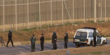 GRA020. MELILLA, 02/12/2014.- Varios subsaharianos permanecen encaramados en la valla de Melilla por la zona cercana al paso fronterizo de Barrio Chino, que está cortado al tránsito desde que a las siete de la mañana se hayan registrado dos intentos de entrada simultánea de dos grupos, con más de medio millar de inmigrantes. EFE/F. G. Guerrero