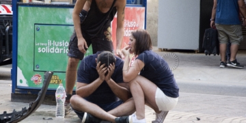 GRA180. BARCELONA, 17/08/2017.- Varios jóvenes permanecen junto a los restos de un vehículo, en el lugar del atropello masivo realizado por una furgoneta que ha arrollado esta tarde a varias personas que paseaban por las Ramblas de Barcelona. Los Mossos d'Esquadra y los equipos de emergencias sanitarias han desplegado un amplio dispositivo en esta zona, en el centro turístico de la capital catalana, frecuentada a diario por miles de turistas, que ha quedado acordonada. EFE/David Armengou