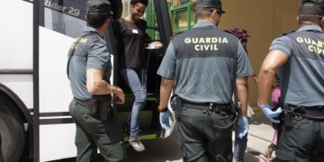 Una mujer sale del autobús que ayer trasladó al grupo de subsaharianos desde el puerto hasta el CETI. / EFE