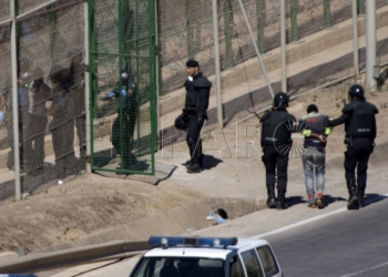GRA055 MELILLA M 13/8/2014.- Dos de los inmigrantes encaramados a la valla de Melilla desde esta madrugada se han bajado de la verja y han sido entregados a Marruecos. Los dos subsaharianos han descendido por una de las escaleras colocadas por la Guardia Civil y, posteriormente, han sido entregados a las autoridades marroquíes por una de las puertas de acceso de la valla.El resto de subsaharinos, entre 60 y 70, permanecen subido en la parte alta del vallado, a una altura de seis metros, visiblemente cansados, tras siete horas.A ambos lados del perimetro, tanto en el lado español como en el marroquí, hay un fuerte despliegue policial.EFE/Francisco G. Guerrero
