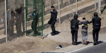 GRA055 MELILLA M 13/8/2014.- Dos de los inmigrantes encaramados a la valla de Melilla desde esta madrugada se han bajado de la verja y han sido entregados a Marruecos. Los dos subsaharianos han descendido por una de las escaleras colocadas por la Guardia Civil y, posteriormente, han sido entregados a las autoridades marroquíes por una de las puertas de acceso de la valla.El resto de subsaharinos, entre 60 y 70, permanecen subido en la parte alta del vallado, a una altura de seis metros, visiblemente cansados, tras siete horas.A ambos lados del perimetro, tanto en el lado español como en el marroquí, hay un fuerte despliegue policial.EFE/Francisco G. Guerrero