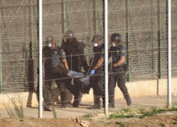 GRA016 MELILLA, 14/08/2014.- Agentes de la Guardia Civil llevan en volandas a uno de los seis inmigrantes que se encontraban en lo alto de malla antitrepa de Melilla tras un nuevo intento de entrada a la ciudad autonóma a través de la valla fronteriza con Marruecos por parte de decenas de inmigrantes subsaharianos. Tras casi dos horas encaramados a la valla los seis inmigrantes han sido obligados a descender en la zona entre vallas y entregados a la gendarmería marroquí. EFE/Francisco G.Guerrero