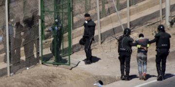 GRA055 MELILLA M 13/8/2014.- Dos de los inmigrantes encaramados a la valla de Melilla desde esta madrugada se han bajado de la verja y han sido entregados a Marruecos. Los dos subsaharianos han descendido por una de las escaleras colocadas por la Guardia Civil y, posteriormente, han sido entregados a las autoridades marroquíes por una de las puertas de acceso de la valla.El resto de subsaharinos, entre 60 y 70, permanecen subido en la parte alta del vallado, a una altura de seis metros, visiblemente cansados, tras siete horas.A ambos lados del perimetro, tanto en el lado español como en el marroquí, hay un fuerte despliegue policial.EFE/Francisco G. Guerrero
