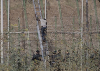 GRA058 MELILLA M 13/8/2014.- Dos de los inmigrantes encaramados a la valla de Melilla desde esta madrugada se han bajado de la verja y han sido entregados a Marruecos. Los dos subsaharianos han descendido por una de las escaleras colocadas por la Guardia Civil y, posteriormente, han sido entregados a las autoridades marroquíes por una de las puertas de acceso de la valla.El resto de subsaharinos, entre 60 y 70, permanecen subido en la parte alta del vallado, a una altura de seis metros, visiblemente cansados, tras siete horas.A ambos lados del perimetro, tanto en el lado español como en el marroquí, hay un fuerte despliegue policial.EFE/Francisco G. Guerrero