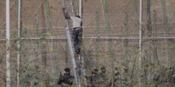 GRA058 MELILLA M 13/8/2014.- Dos de los inmigrantes encaramados a la valla de Melilla desde esta madrugada se han bajado de la verja y han sido entregados a Marruecos. Los dos subsaharianos han descendido por una de las escaleras colocadas por la Guardia Civil y, posteriormente, han sido entregados a las autoridades marroquíes por una de las puertas de acceso de la valla.El resto de subsaharinos, entre 60 y 70, permanecen subido en la parte alta del vallado, a una altura de seis metros, visiblemente cansados, tras siete horas.A ambos lados del perimetro, tanto en el lado español como en el marroquí, hay un fuerte despliegue policial.EFE/Francisco G. Guerrero