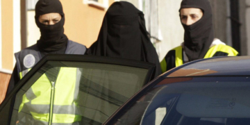Una de las mujeres detenidas en Melilla, vestida con "niqab", una prenda de color negro que cubre por completo el cuerpo y el rostro de la mujer, a la salida de la vivienda donde ha sido apresada en la ciudad autónoma, donde se han producido otras dos detenciones, un hombre y una menor, en el marco de una operación contra una red de captación y envío de mujeres a la organización terrorista yihadista DAESH. EFE/F. G. Guerrero