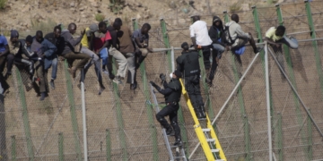 GRA059 MELILLA M 13/8/2014.- Dos de los inmigrantes encaramados a la valla de Melilla desde esta madrugada se han bajado de la verja y han sido entregados a Marruecos. Los dos subsaharianos han descendido por una de las escaleras colocadas por la Guardia Civil y, posteriormente, han sido entregados a las autoridades marroquíes por una de las puertas de acceso de la valla.El resto de subsaharinos, entre 60 y 70, permanecen subido en la parte alta del vallado, a una altura de seis metros, visiblemente cansados, tras siete horas.A ambos lados del perimetro, tanto en el lado español como en el marroquí, hay un fuerte despliegue policial.EFE/Francisco G. Guerrero