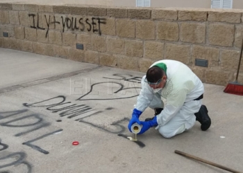 El equipo de limpieza retirando los restos de las pintadas de la muralla de la cuesta de la Florentina.