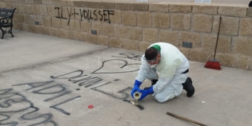 El equipo de limpieza retirando los restos de las pintadas de la muralla de la cuesta de la Florentina.
