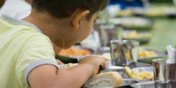 Un niño comiendo en un colegio.