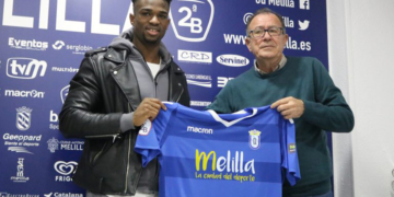 Moha Traoré y Antonio García Jáuregui sostienen la camiseta de la Unión Deportiva Melilla durante la presentación del futbolista ante los medios de comunicación.