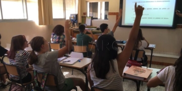 Unos niños atendiendo en clase a su maestra.