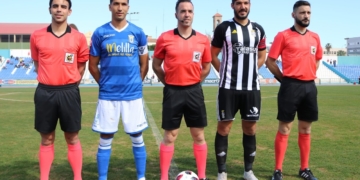 El trío arbitral, junto a los capitanes de	una y otra escuadra, destacando que el veterano melillense Mahanan volvía en la matinal de ayer al once inicial de los azulinos.
