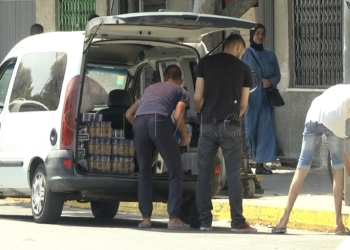 Imagen de un grupo de jóvenes descargando una furgoneta de mercancía.