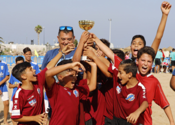 Los jugadores del CF Rusadir alevín alzan el trofeo que les acredita como campeones de la liga de fútbol playa 2019.