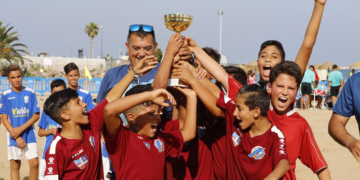 Los jugadores del CF Rusadir alevín alzan el trofeo que les acredita como campeones de la liga de fútbol playa 2019.