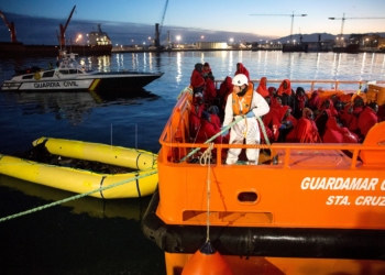GRAF1454. MÁLAGA,13/01/2018.- Varias de las 55 personas de origen subsahariano que han llegado al puerto de Málaga rescatados a última hora de esta tarde en el mar de Alborán mientras navegaban en una patera, la segunda del día de hoy, esperan para ser atendidos por miembros de la Cruz Roja. EFE/Daniel Pérez