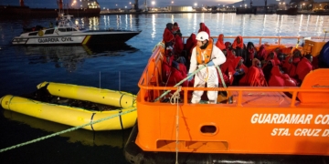 GRAF1454. MÁLAGA,13/01/2018.- Varias de las 55 personas de origen subsahariano que han llegado al puerto de Málaga rescatados a última hora de esta tarde en el mar de Alborán mientras navegaban en una patera, la segunda del día de hoy, esperan para ser atendidos por miembros de la Cruz Roja. EFE/Daniel Pérez
