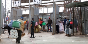 GRAF1091. MELILLA, 12/09/2018.- Varias personas en la frontera de Barrio Chino, en Melilla, que dedica la mitad del día a los porteadores y es la que más aumentó su tráfico el año pasado, al ser utilizada por 1.563.568 en ambos sentidos, un 11,56 % más que en 2016, lo que da una idea del auge del comercio atípico en los últimos tiempos en Melilla. Melilla, que tiene cuatro pasos fronterizos con Marruecos por los que cruzan cada año en ambos sentidos más de 20 millones de personas y casi cinco millones de vehículos, está en vilo por el futuro de su aduana comercial, cerrada desde hace 43 días por decisión unilateral del país vecino. EFE/ F.G. Guerrero