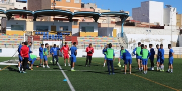 El cuerpo técnico de la entidad melillense dando consignas en el campo federativo de La Espiguera.