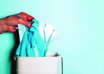 Pandemic is over concept. Quarantine end. Stop Coronavirus. Hand throws medical masks to trash bin after coronavirus pandemic. Copy space. Stay safe. Health protection equipment.