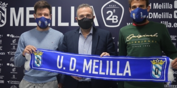 Iker Hernández y Sergio Parla sostienen, junto al presidente de la entidad azulina, una bufanda de la Unión Deportiva Melilla.