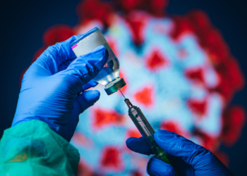 Coronavirus Covid-19 Protection and Vaccine. Doctor drawing up solution from vaccine bottle and filling syringe injection for patient vaccination in medical clinic, Coronavirus in background