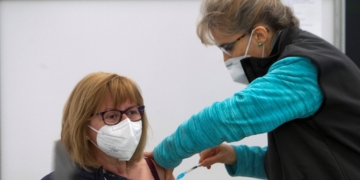 VIGO, 17/04/2021.- Una mujer recibe una dosis de la vacuna de AstraZeneca, este sábado en las instalaciones del Ifevi, donde se está vacunando hoy a 3.500 ciudadanos de entre 60 y 65 años con AstraZeneca y 5.400 mañana, con Pfizer, de 79 a 70 años. EFE/ Salvador Sas