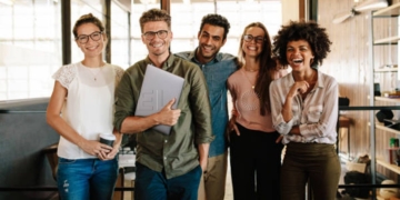 Portrait of creative business team standing together and laughing. Multiracial business people together at startup.