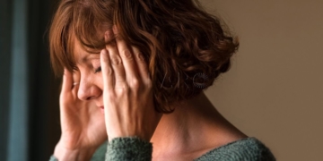 Close-up shot of a woman suffering from a headache and rubbing her temples  at home