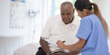 An African senior gentleman speaks with his doctor during a routine check-up in the doctors office