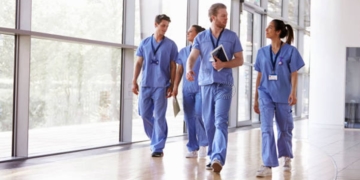 Four healthcare workers in scrubs walking in corridor