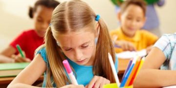 Portrait of lovely girl drawing with colorful pencils at lesson