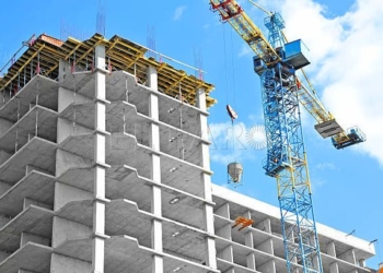 Crane and building under construction against blue sky