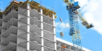 Crane and building under construction against blue sky