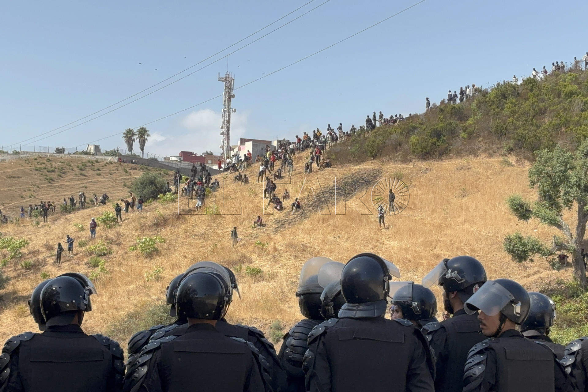 FOTODELDÍA - Castillejos (Marruecos), 15/08/2026.- Las fuerzas de Seguridad de Marruecos vigilan este sábado a decenas de migrantes subsaharianos que vinieron a las afueras de la urbe fronteriza de Fnideq (Castillejos en español). Fuentes de Seguridad marroquíes indicaron a EFE que el incidente se registró en una zona montañosa, en las afueras de Castillejos y al suroeste de Ceuta. EFE/Mohamed Siali